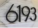 Close-up of the house number '6193' mounted on a decorative white-washed wooden plaque at 6193 Charring Cross Ct, Lithonia, GA 30058
