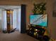 Well-lit living area featuring a large TV, decorative accents, and neutral-toned carpet at 6193 Charring Cross Ct, Lithonia, GA 30058