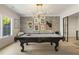 Spacious game room with a black pool table, brick accent wall and modern chandelier at 214 Kenneth Drive, Alpharetta, GA 30009