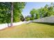 Large backyard with a white fence, green lawn, a fire pit and mature trees at 2253 Carrington Dr, Ellenwood, GA 30294