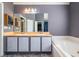 Bathroom featuring double sinks with gray cabinets, bathtub, and large mirror on accent wall at 2253 Carrington Dr, Ellenwood, GA 30294