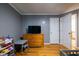 Bedroom with hardwood floors, gray accent wall, dresser with television and doorway at 2253 Carrington Dr, Ellenwood, GA 30294