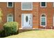 Up-close view of the brick home's white front door, complemented by blooming flowers and lush green bushes at 2253 Carrington Dr, Ellenwood, GA 30294