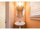 Powder room with pedestal sink, round mirror and ornate patterned wallpaper at 2253 Carrington Dr, Ellenwood, GA 30294