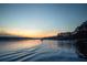 Sunset view of lake with calm waters, trees, and a distant motorboat at 1160 Lake Shore Overlook, Alpharetta, GA 30005