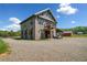 Barn exterior featuring a balcony, covered carport, and a gravel driveway with lush greenery at 96 Landers Ne Rd, Rydal, GA 30171