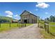 Exterior shot of a modern, two-story barn with gravel drive on a sunny day at 96 Landers Ne Rd, Rydal, GA 30171