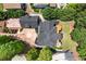 An aerial view of a home with a dark gray roof and well-manicured lawn surrounded by mature trees at 4290 Bobbins Way, Cumming, GA 30041
