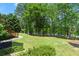 Manicured backyard lawn with lush trees and lake views beyond at 4290 Bobbins Way, Cumming, GA 30041