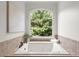Bathroom features a soaking tub under a large window overlooking backyard at 4290 Bobbins Way, Cumming, GA 30041