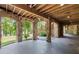 Covered outdoor patio with stone columns and wood ceiling leading to staircase and backyard at 4290 Bobbins Way, Cumming, GA 30041