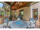 Covered porch with a stone fireplace, grill, ceiling fan, and beautiful wooded views at 4290 Bobbins Way, Cumming, GA 30041