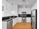 Modern kitchen featuring white cabinets, stainless steel appliances, black subway tile, and wood flooring at 860 Peachtree Ne St # 2815, Atlanta, GA 30308