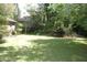 Overgrown backyard featuring a spacious lawn with mature trees and shrubs, offering a private setting at 5170 Chamblee Dunwoody Rd, Atlanta, GA 30338