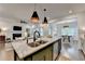 An open kitchen boasts an island with a granite countertop and stylish pendant lighting at 5650 Bergeson Ways, Cumming, GA 30028