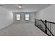 This loft features neutral walls and carpet, a ceiling light, and a dark railing at 5650 Bergeson Ways, Cumming, GA 30028