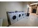 A clean laundry room features multiple white front-loading washing machines on a tile floor at 20 Marietta St. Nw #12D, Atlanta, GA 30303