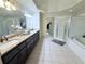 Luxurious bathroom featuring dual sinks, granite countertops, a glass-enclosed shower, and a soaking tub at 6795 Preston Glen Dr, Alpharetta, GA 30005