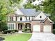 Charming two-story brick home with manicured lawn, elegant landscaping, and attached two-car garage at 6795 Preston Glen Dr, Alpharetta, GA 30005