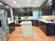 Well-lit kitchen featuring dark wood cabinets, stainless steel appliances, and a central island with a marble countertop at 6795 Preston Glen Dr, Alpharetta, GA 30005