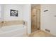 Bright bathroom featuring a soaking tub, tiled shower with glass enclosure, and neutral stone flooring at 2864 White Oak Dr, Decatur, GA 30032