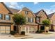 Attractive brick townhome boasts a two-car garage, complemented by lush green landscaping at 4150 Cedar Bridge Walk, Suwanee, GA 30024