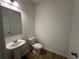 Clean half bathroom featuring a pedestal sink, new toilet, modern mirror, and wood-look floors at 5377 Heron Bay Blvd, Locust Grove, GA 30248