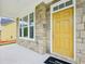 Close-up of the front door and stone facade with a yellow front door and an Ashton Woods welcome mat at 5377 Heron Bay Blvd, Locust Grove, GA 30248