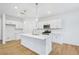 Modern white kitchen with quartz countertops, stainless steel appliances, an island, and hardwood floors at 5377 Heron Bay Blvd, Locust Grove, GA 30248