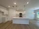 Bright, modern kitchen with a large island, white cabinets, stainless steel appliances, and hardwood floors at 5377 Heron Bay Blvd, Locust Grove, GA 30248