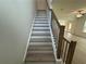 Staircase with carpeted steps and wood railing with black iron spindles at 5377 Heron Bay Blvd, Locust Grove, GA 30248