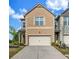 Charming two-story home featuring a light brick facade, attached garage, and well-manicured landscaping at 7884 Rock Rose Ln, Fairburn, GA 30213
