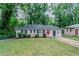 Charming single-story home with a well-maintained lawn, a red door, and complemented by lush green trees at 2529 Habersham Dr, Decatur, GA 30032