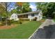 Spacious front yard with mature trees and a charming facade, creating a serene residential setting at 7300 Wynhill Dr, Sandy Springs, GA 30328