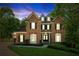 Twilight view of an elegant two-story brick home with manicured lawn and lush landscaping at 4750 Spring Wood Trce, Cumming, GA 30041