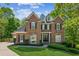 Elegant two-story brick home featuring dormer windows, a manicured lawn, and lush landscaping at 4750 Spring Wood Trce, Cumming, GA 30041