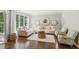 Bright living room with hardwood floors, white sofas, and a large window overlooking the yard at 4750 Spring Wood Trce, Cumming, GA 30041