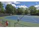 Community tennis courts with blue and green surfaces, benches, and protective fencing at 4750 Spring Wood Trce, Cumming, GA 30041