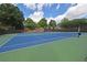 Well-maintained community tennis courts with a blue and green surface, surrounded by fencing and greenery at 4750 Spring Wood Trce, Cumming, GA 30041