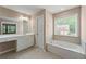 Bathroom featuring double vanity and soaking tub by a window offering natural light at 550 Bayswater Way, Suwanee, GA 30024