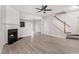 Bright living room featuring a fireplace, a ceiling fan, and hardwood flooring leading to a staircase at 1310 Kilmington Ct, Alpharetta, GA 30009