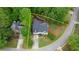 An aerial view of a two-story home with a gray roof, red door, green grass, mature trees, and long driveway at 681 Braidwood Nw Ter, Acworth, GA 30101