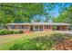 All brick ranch home featuring a covered parking area and meticulously maintained lawn at 205 Corinth Ct, Roswell, GA 30075