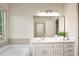 Bright bathroom features a large mirror, white cabinets, granite countertops, and a tub beneath a window at 275 Carriage Chase, Fayetteville, GA 30214
