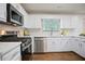Modern kitchen with stainless steel appliances, white cabinetry, and hardwood floors at 275 Carriage Chase, Fayetteville, GA 30214