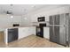 Corner view of modern kitchen with stainless appliances, white cabinets, and wood-look floors at 235 Centennial Cir, Canton, GA 30114