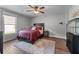 Cozy bedroom featuring hardwood floors, ceiling fan, and a large window for natural light at 2111 Democracy Dr, Buford, GA 30519