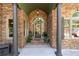 Stone entryway featuring decorative columns, an arched door, and manicured landscaping details at 2111 Democracy Dr, Buford, GA 30519