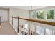 Hallway featuring decorative wood trim railing and natural light throughout at 1520 Ethans Way, Mcdonough, GA 30252