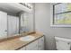 Bright bathroom featuring a granite countertop, white cabinets, and a window above the toilet at 204 Holly Creek Way, Woodstock, GA 30188